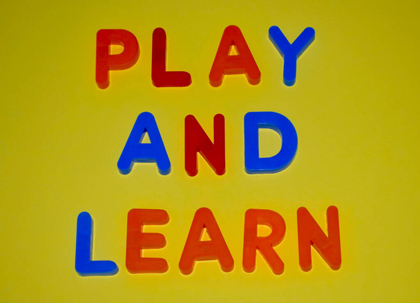 Jugar y aprender palabras escritas con diferentes bloques de letras de colores dispuestos sobre un fondo amarillo
 - Foto, imagen
