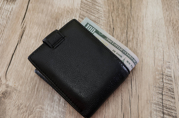 dollars in a black wallet on a wooden background. View from above. - 写真・画像