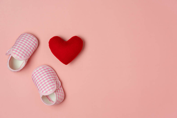 Top view aerial image of decoration Happy mothers day holiday background or women & kid fashion concept.Flat lay red love heart and baby shoes on modern pink paper.Free space for creative design text. - Photo, Image