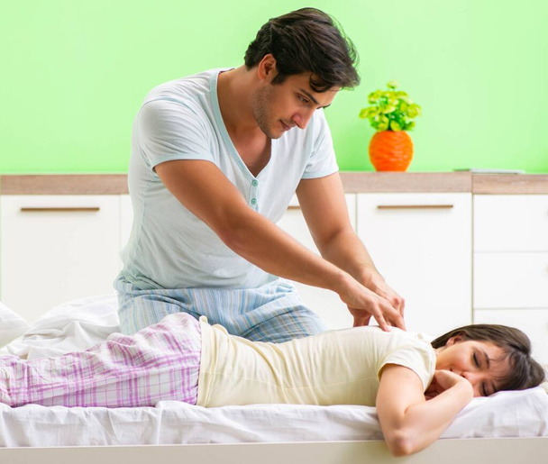 Man doing massage to his wife in bedroom - Zdjęcie, obraz