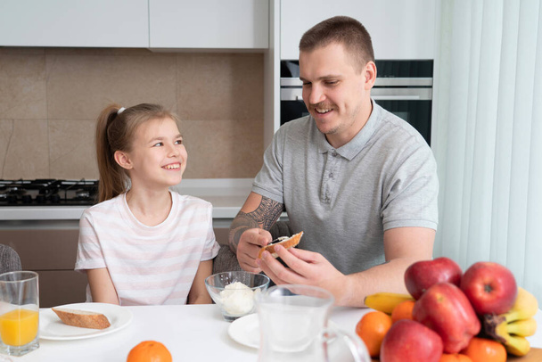 padre e hija desayunando en la cocina
 - Foto, Imagen