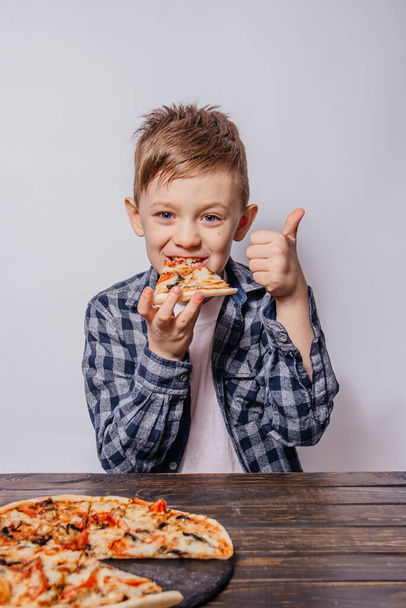 Büyük bir zevkle bir dilim pizza yiyor ve beyaz bir arka planda kendini gösteriyor. - Fotoğraf, Görsel