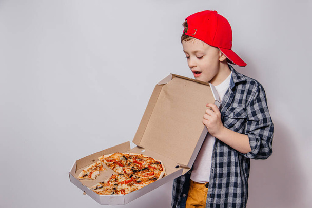 srác nyit egy doboz pizza nagy lelkesedéssel és türelmetlenséggel fehér háttér - Fotó, kép