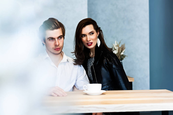 beautiful couple in a cafe at a table drinks coffee and talking about something - 写真・画像