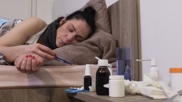 Mujer enferma comprobando la temperatura corporal con termómetro
 - Imágenes, Vídeo