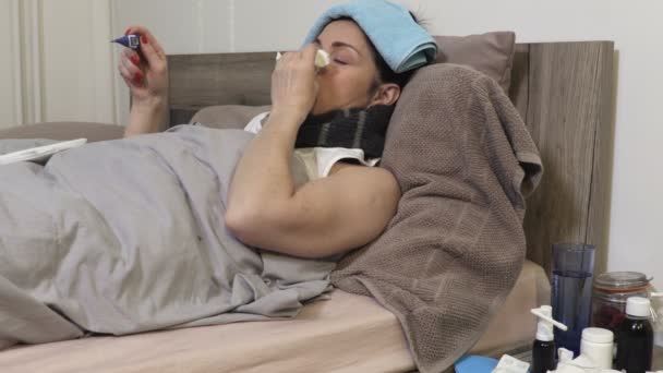 Nemocná žena s tekoucím nosem a bolestí v krku při teplotě s digitálním teploměrem - Záběry, video