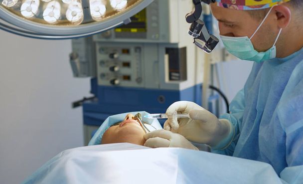 Несколько врачей, окружающих пациента на операционном столе во время работы. Командные хирурги за работой в операционной
 - Фото, изображение