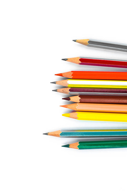 Scattered row of different colored wood pencil crayons arranged together in a line format in front of a white background - Photo, Image