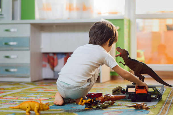 Adorable toddler playing with dinosaurs around lots of toys at home. Stay home. - Foto, immagini