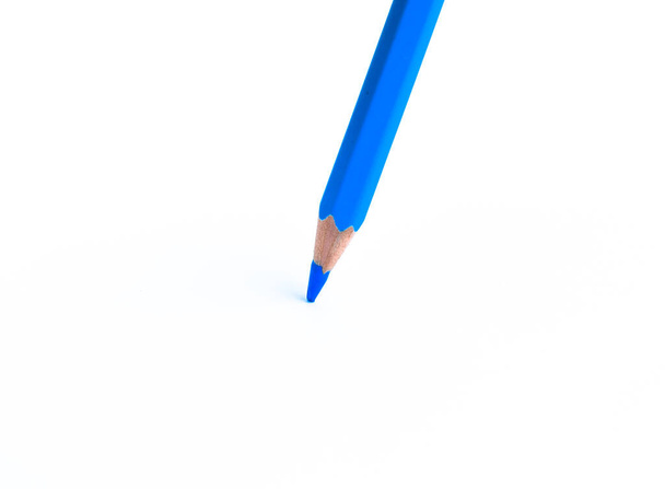 Ένα ενιαίο μπλε χρώμα ξύλο μολύβι μαρκαδόρο τοποθετείται σε ένα απομονωμένο λευκό φόντο χαρτί - Φωτογραφία, εικόνα