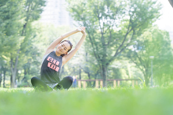 Asian young woman doing yoga in the park full of green - Photo, Image