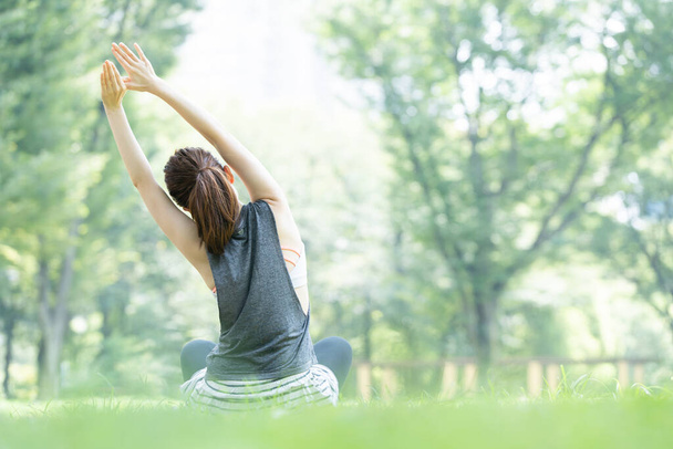 Azjatka młoda kobieta uprawia jogę w parku pełnym zieleni - Zdjęcie, obraz