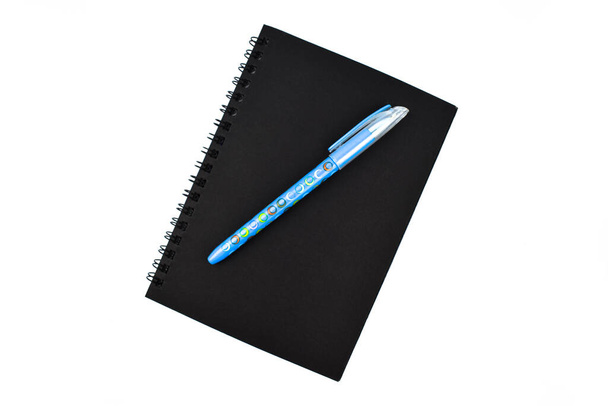 Világoskék színű toll egy egyszerű, közepes méretű, zárt fekete papírnapló tetején. - Fotó, kép