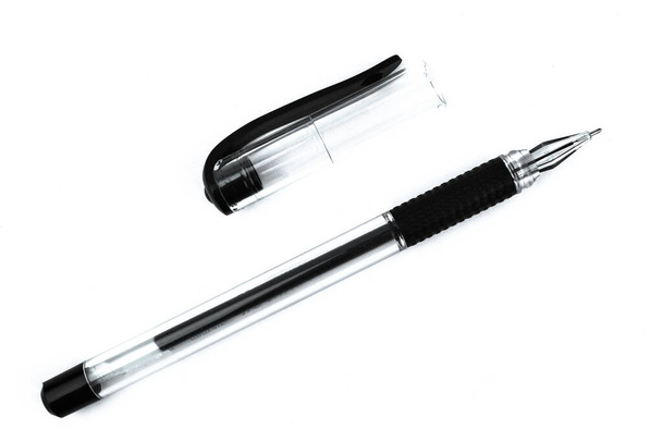 Uma caneta esferográfica de cor preta e seu boné espalhados em cima de um fundo isolado branco
 - Foto, Imagem