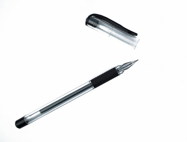 Black colored ball point pen and its cap scattered on top of a white isolated background - Photo, Image