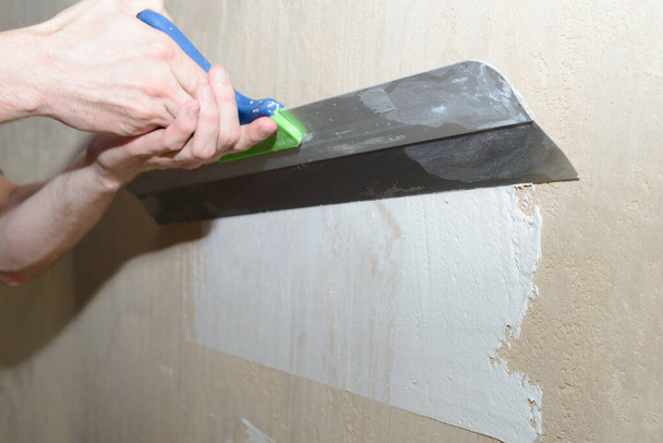 Puttying the wall with white plaster putty using a wide spatula - 写真・画像