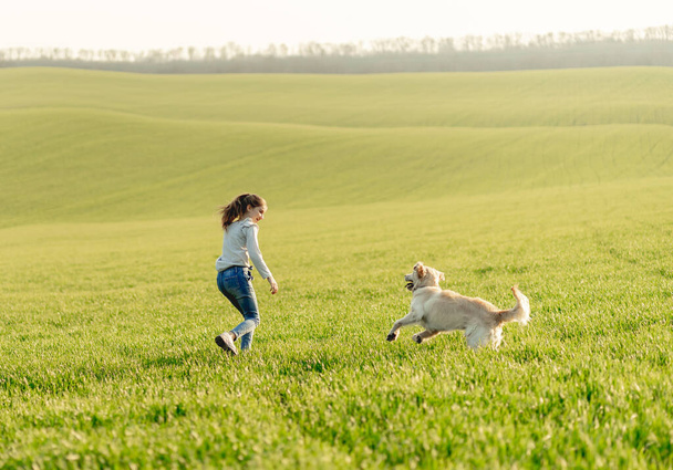 Girl with dog on sunny field - Valokuva, kuva