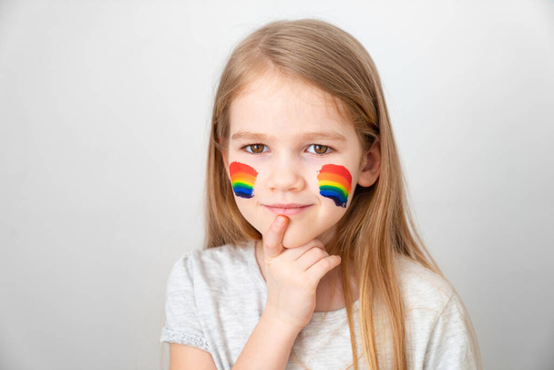 child girl painted cheeks a rainbow. stay home.  - Zdjęcie, obraz