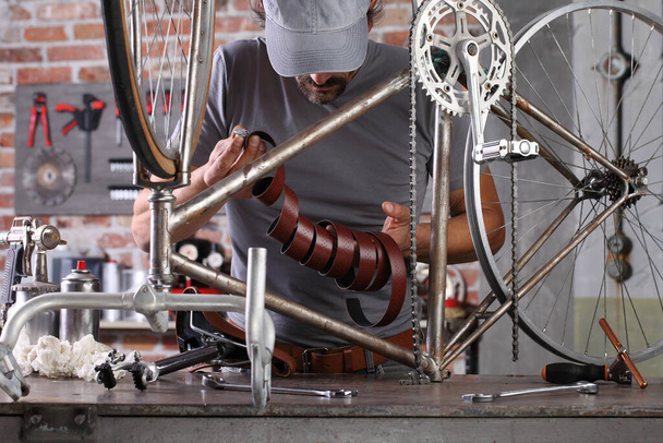 hombre reparar la bicicleta vintage en taller de garaje en el banco de trabajo con herramientas, concepto de bricolaje - Foto, Imagen