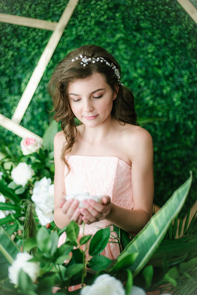 Menina atraente em um vestido rosa romântico entre vegetação tropical e orquídeas brancas, rosas e lírios. Beleza e moda
 - Foto, Imagem