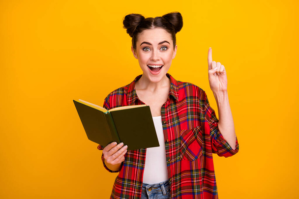 Photo of crazy student lady open mouth hold book read adventure story literature lesson raise finger have question answer wear casual plaid shirt isolated yellow color background - Foto, Imagen