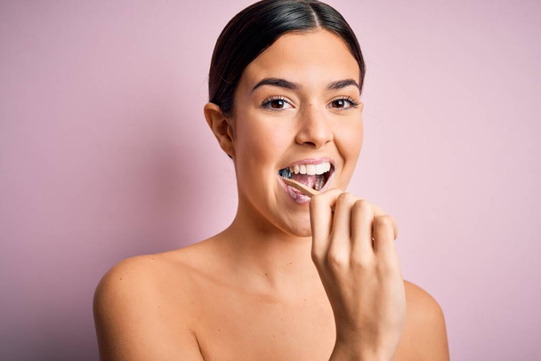 Young beautiful brunette woman brushing her teeth using tooth brush and oral paste, cleaning teeth and tongue as healthy health care morning routine - Foto, Imagem