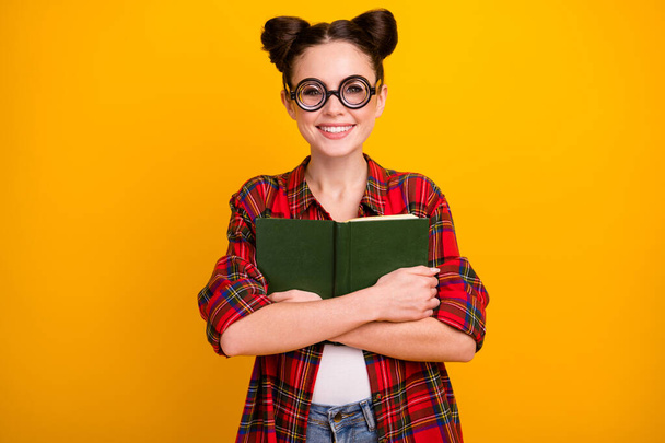 Photo of pretty crazy lady two buns hold book close to chest love story favorite historic novel wear geek vision specs casual checkered shirt isolated yellow color background - Photo, image