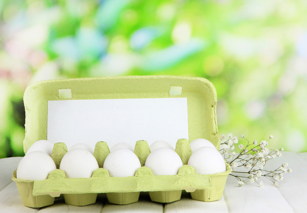 Eggs in paper tray on wooden table on natural background - Valokuva, kuva
