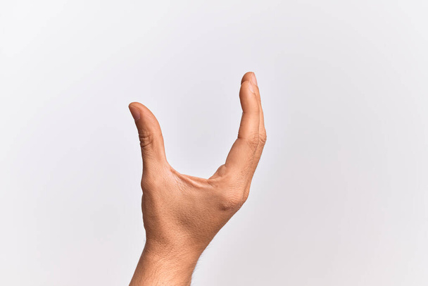 Hand eines kaukasischen jungen Mannes mit Fingern über isoliertem weißem Hintergrund, der unsichtbare Dinge pflückt und nimmt, während er ein Objekt mit Fingern hält, die Raum zeigen - Foto, Bild