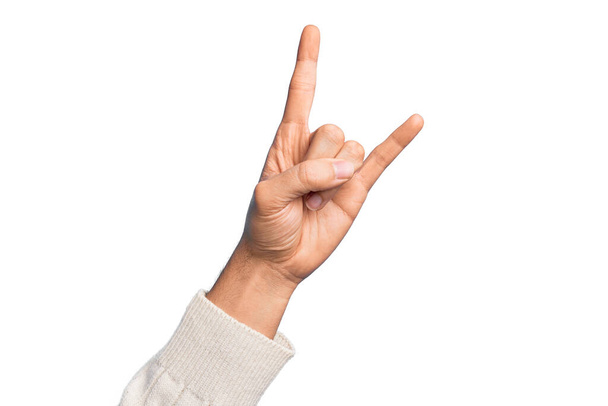 Рука кавказского юноши показывает пальцы на изолированном белом фоне жестом рок-н-ролла символ, показывающий непристойные рога жест - Фото, изображение