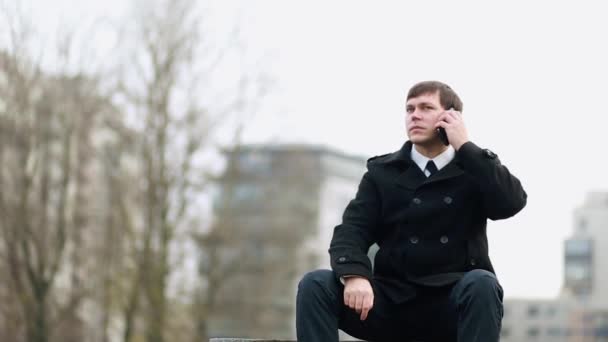 A businessman sitting on a bench answers the phone. - Materiaali, video