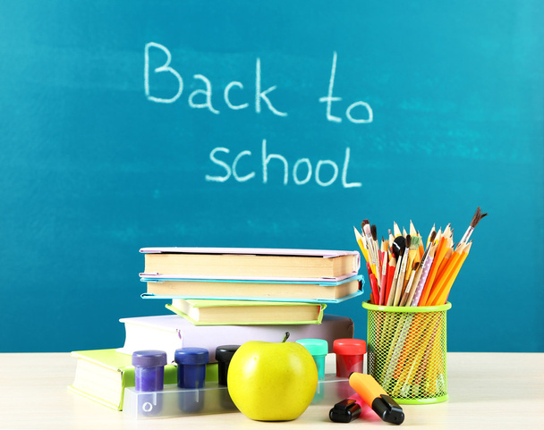 School supplies on table on blackboard background - Photo, image