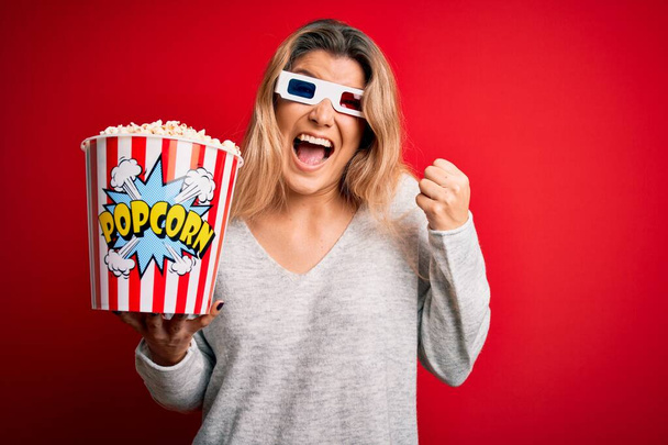 Fiatal gyönyörű szőke nő filmet néz 3D-s szemüveget eszik popcorns sikoltozó büszke és ünnepli győzelem és a siker nagyon izgatott, éljenzés érzelem - Fotó, kép