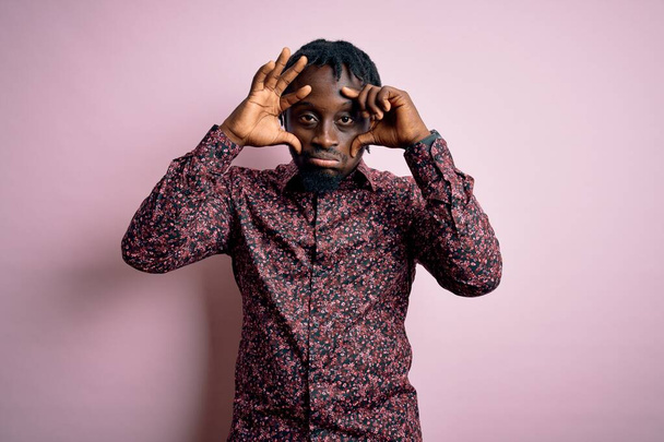 Young handsome african american man wearing casual shirt standing over pink background Trying to open eyes with fingers, sleepy and tired for morning fatigue - Foto, immagini