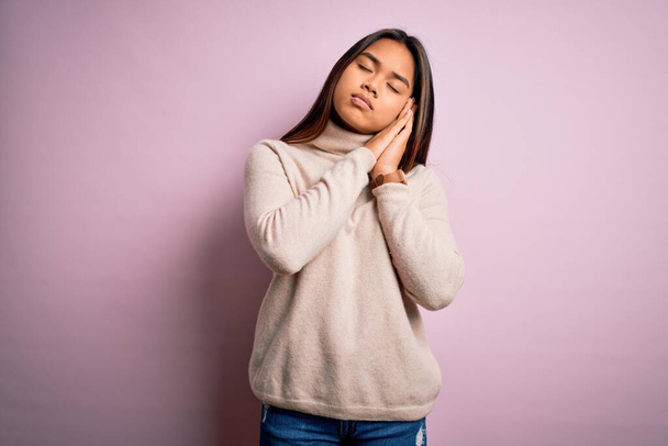 Young beautiful asian girl wearing casual turtleneck sweater over isolated pink background sleeping tired dreaming and posing with hands together while smiling with closed eyes. - Photo, image