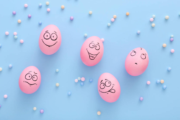 Lustige rosa Eier mit Gesichtsgefühl auf blauem Hintergrund - Foto, Bild