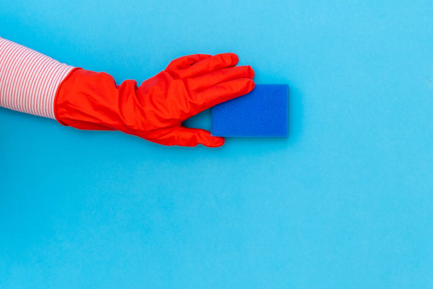 Mano de mujer en guante protector rojo con limpiaparabrisas azul en el fondo azul. Vista superior, espacio de copia
. - Foto, imagen