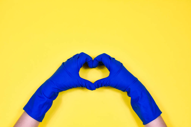 Working hands in rubber protective gloves show the heart. Early spring or regular cleaning. The concept of cleanliness. - Foto, imagen