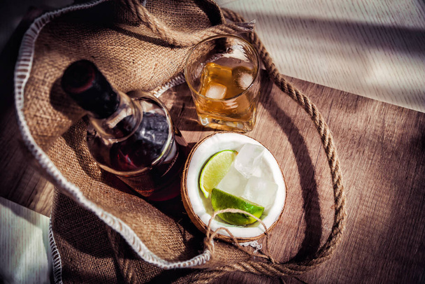 Rum com gelo e coco, uma garrafa de rum com limão
 - Foto, Imagem