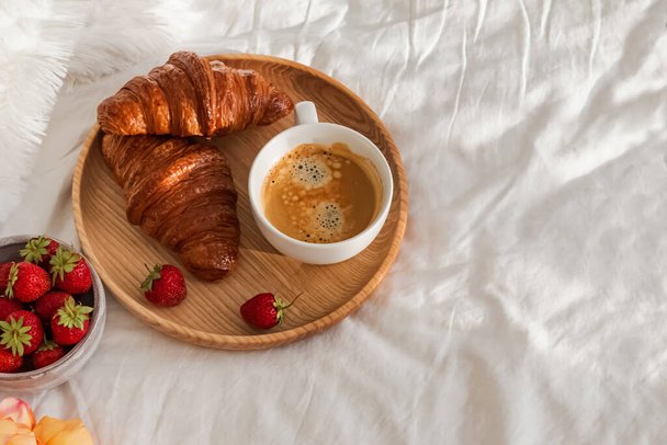 Breakfast in bed, tray with cup of coffee, fresh croissants and strawberries - Fotografie, Obrázek