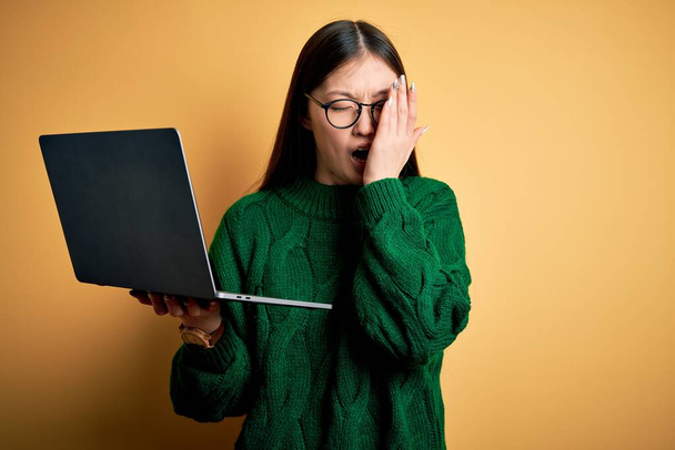 Mladá asijská byznysmena nosí brýle a pracuje s počítačovým laptopem. Tvář bolí bolestí. - Fotografie, Obrázek