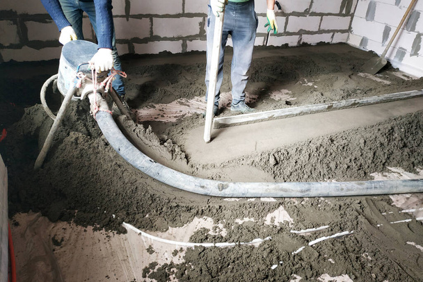 El trabajador realiza una regla de suelo de arena y cemento por encima de la calefacción por suelo.2020
 - Foto, imagen