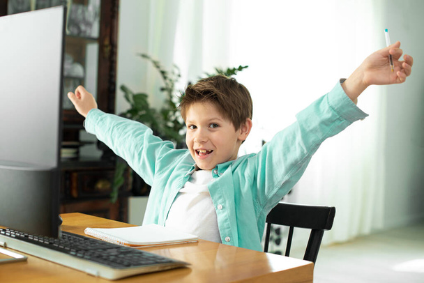 Distance learning in quarantine in coronavirus. Lifestyle. Portrait of successful boy winner with raised hands. Beautiful shouting, isolated. Happy cute child celebrating success with joy - Foto, immagini