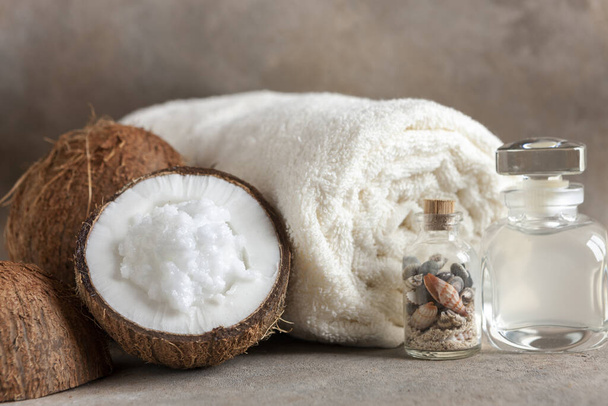 Close-up of Coconut, soft towels, coconut essence, coconut cream and seashells. Spa concept, beauty and health salon, cosmetics store. - Fotó, kép