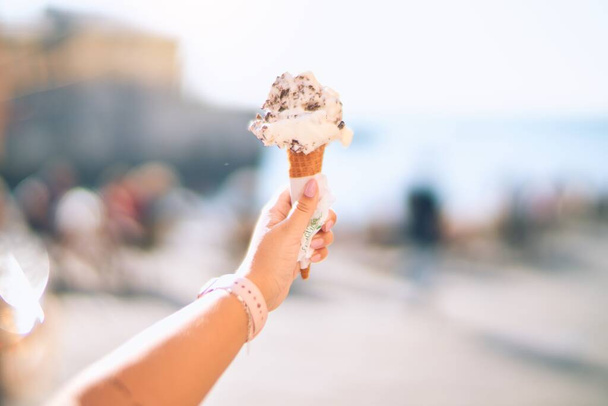 Рука тримає конус морозива в місті
 - Фото, зображення