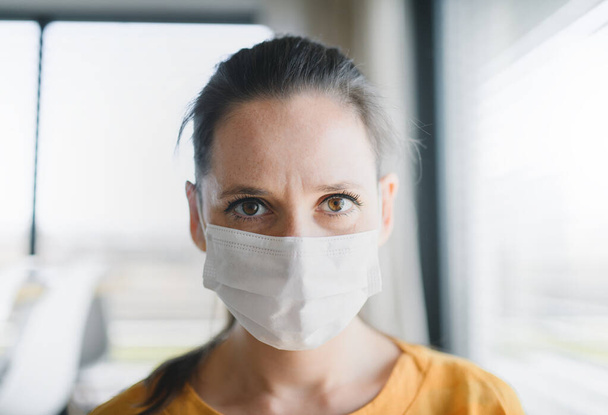 Woman with face mask indoors at home, Corona virus and quarantine concept. - Fotó, kép
