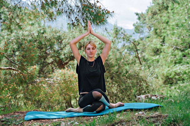 Woman doing yoga poses outside and beautiful view of mountains and forest - Photo, Image