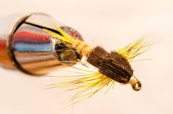 Macro vue de dessus d'une seule mouche de pêche jaune dans un étau sur un fond blanc
 - Photo, image