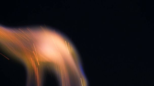 Makrofoto von Bonfire funks. Feuerflammen lodern, lodern. Explosionsartige Mikrofunkeln. Mini-Feuerwerk. Dreharbeiten auf roter Kamera noch auf schwarzem Hintergrund. Funke Poster, Banner, Tapete, Textur. - Foto, Bild