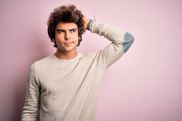 Young handsome man wearing casual t-shirt standing over isolated pink background confuse and wondering about question. Uncertain with doubt, thinking with hand on head. Pensive concept. - Foto, Bild